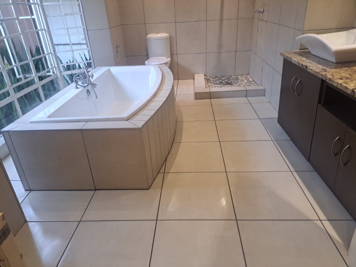 Spacious bathroom with corner tub, walk-in shower and granite vanity