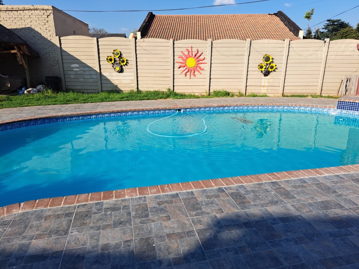 Swimming pool with stone-look tile paving and garden
